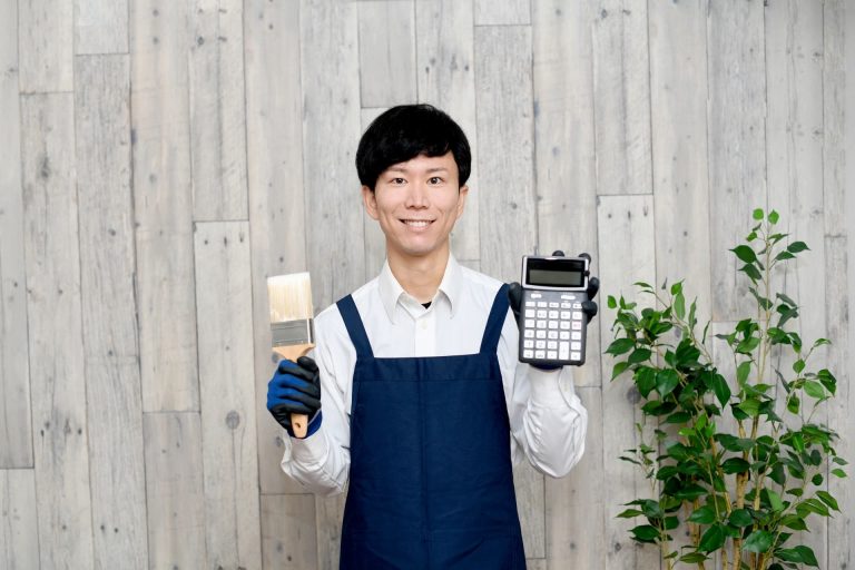 塗装のブラシと電卓を持つ男性